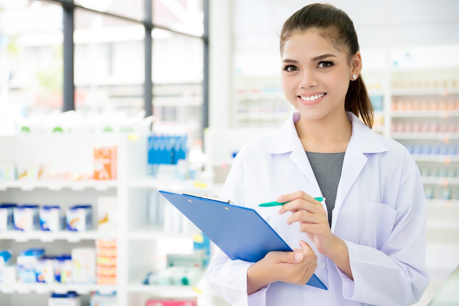 Smiling Asian female pharmacist working in chemist shop or pharmacy