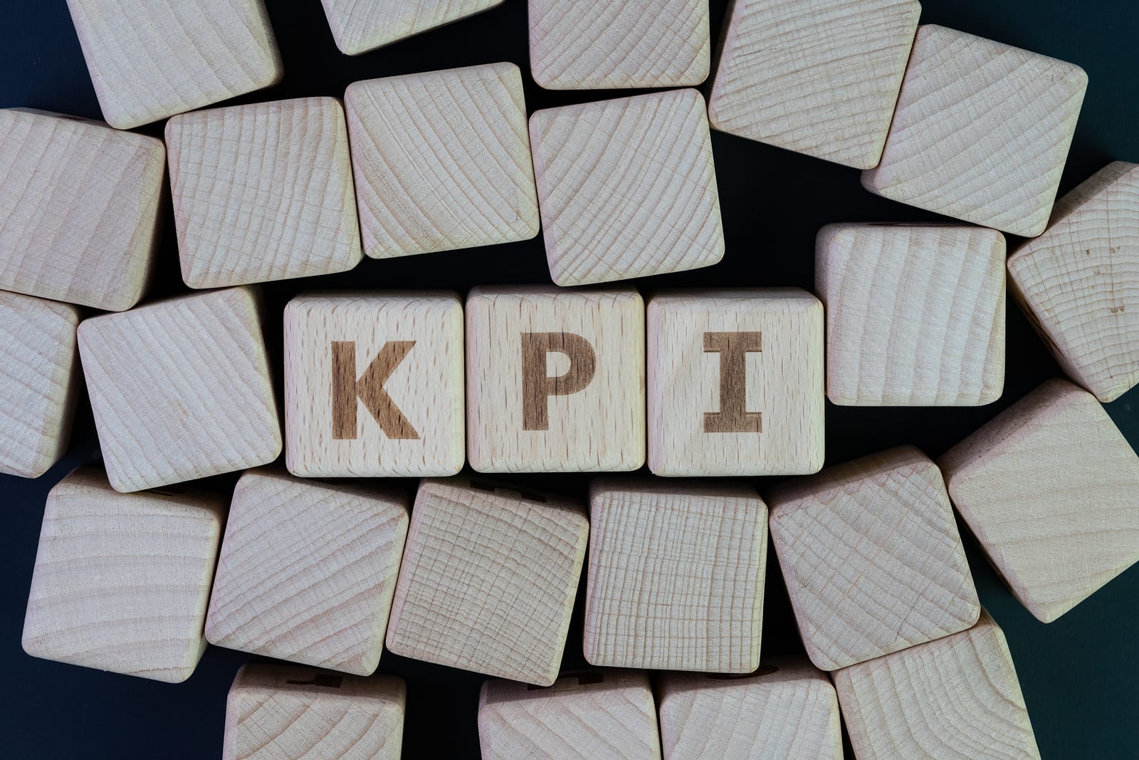 KPI, Key Point Indicator business success measurement target and goal management concept, cube wooden block with alphabet building the word KPI on blackboard.