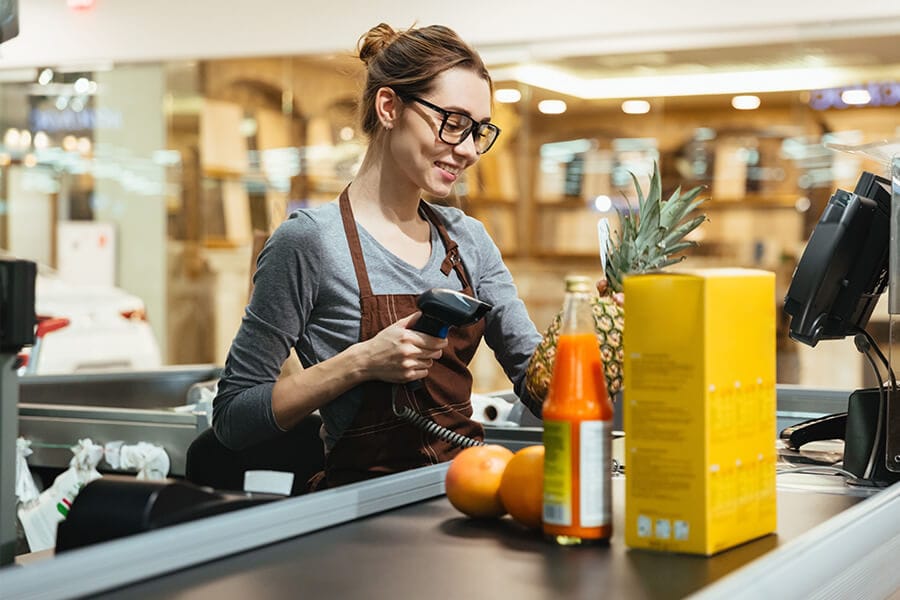 Smiling female cashier scanning grocery items